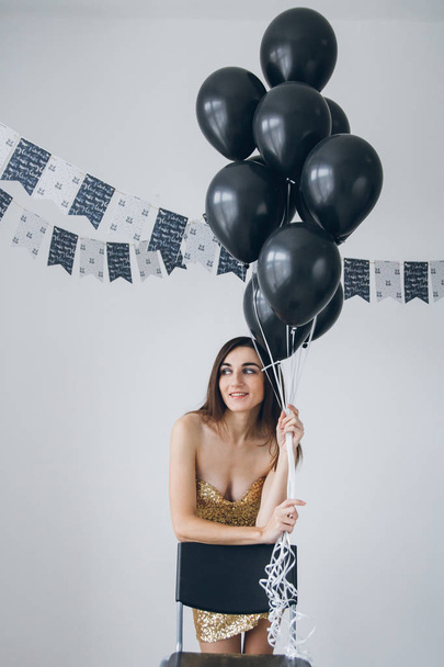 Girl in a gold dress with black balloons - Foto, Bild