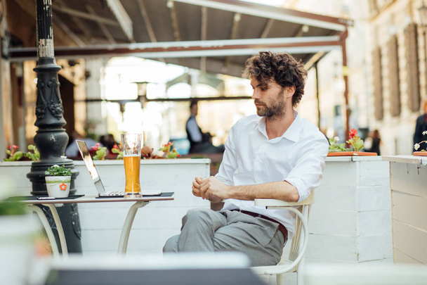 handsome elegant man sitting outside ar terrace drinking beer - Фото, изображение