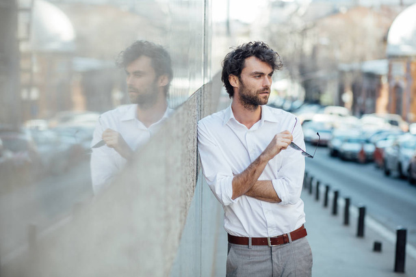 handsome elegant man stanting outside against a gray wall - 写真・画像