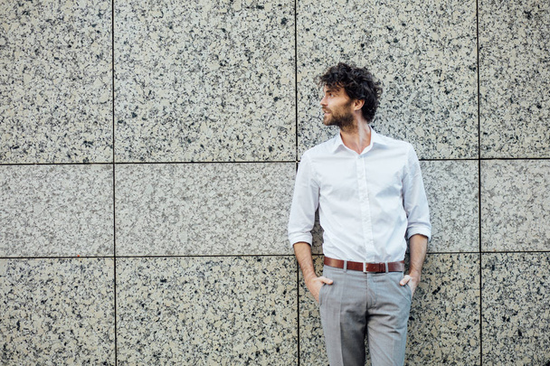 handsome elegant man stanting outside against a gray wall - Foto, Imagem