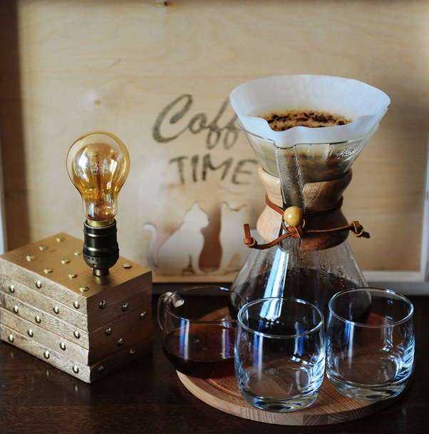 Альтернативный кофе пивоварения в фильтре. Стеклянные стаканы. Настольная лампа с лампой Эдисона
 - Фото, изображение
