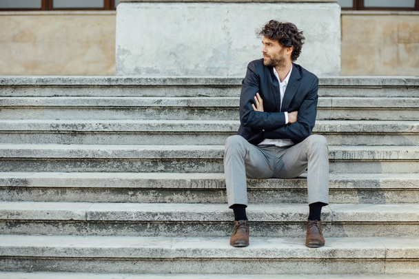 adult and elegant man sitting outside on the stairs - Photo, image