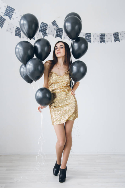 Girl in a gold dress with black balloons - Fotó, kép