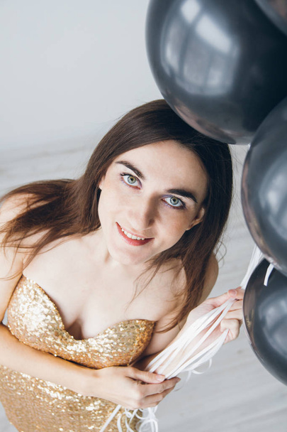 Girl in a gold dress with black balloons - Foto, immagini