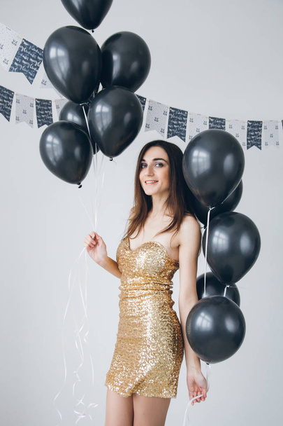 Girl in a gold dress with black balloons - Fotoğraf, Görsel