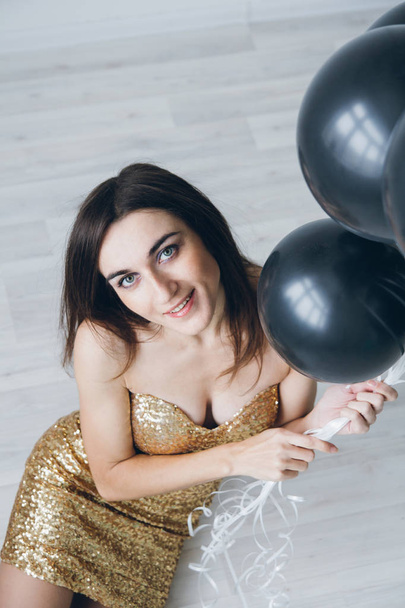 Girl in a gold dress with black balloons - Фото, изображение