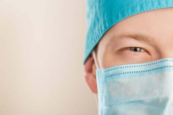 male surgeon in mask gazing and  looking at camera on grey background, close up - Foto, Imagen