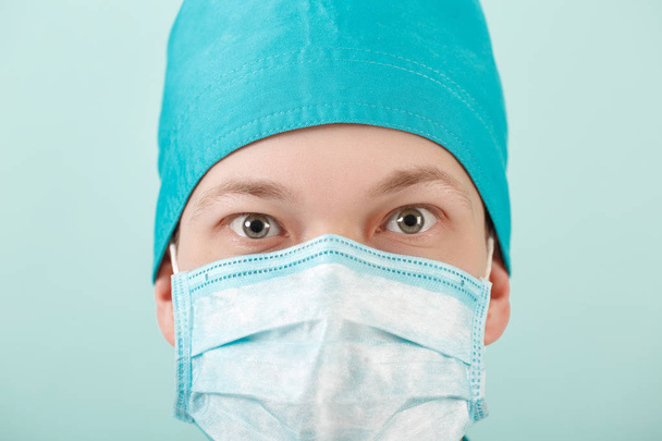 male surgeon in mask looking at camera on blue background, close up - Фото, изображение