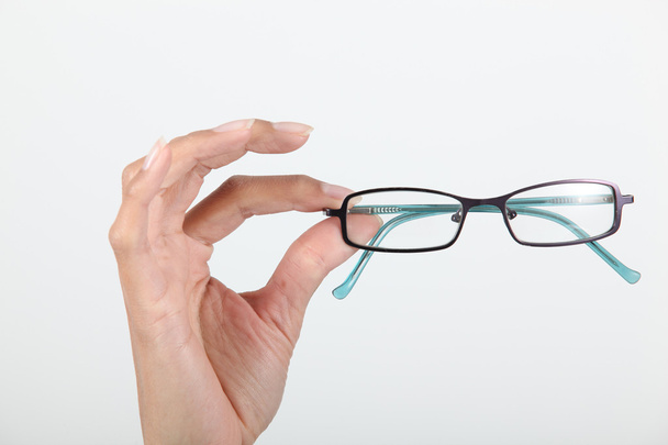 Hand holding pair of eyeglasses - Фото, изображение