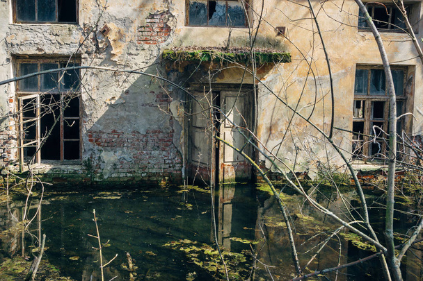 Antigua casa abandonada con paredes peladas está inundada de agua
 - Foto, imagen