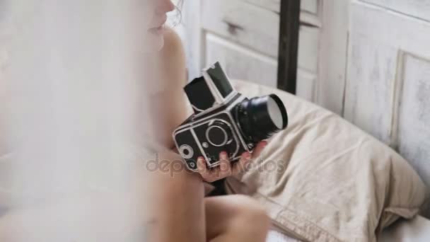 Photographer taking photo on old moving-film camera. Young woman in pajamas taking photos. View through the curtain. - Imágenes, Vídeo