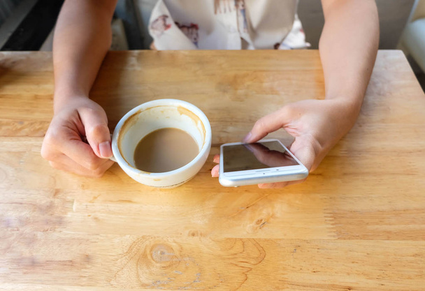 Woman using mobile phone and drink a cup of coffee, close up - Photo, image