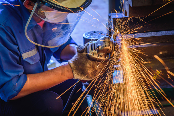 Ağır sanayi işçisi elektrikli tekerlekli kıvılcım ile Çelik fabrikasında çelik yapısı üzerinde taşlama kullanılan. - Fotoğraf, Görsel
