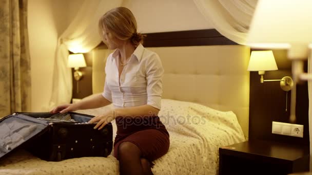 Beautiful young woman puts things into a suitcase and do not forget about her credit card - Πλάνα, βίντεο