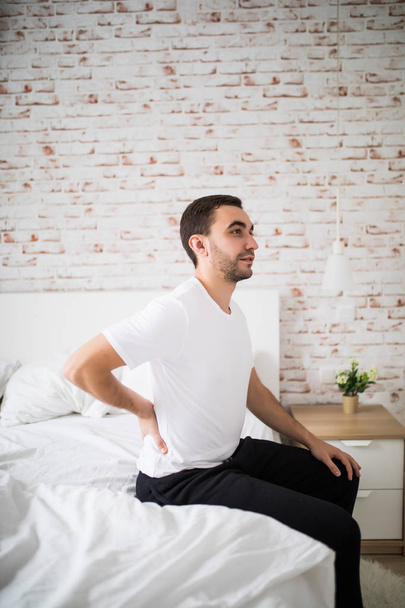 Ο άνθρωπος ξυπνήσει το πρωί και να αισθάνεται τον πόνο στην πλάτη στο κρεβάτι - Φωτογραφία, εικόνα