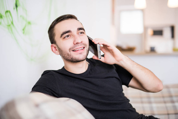 Portret młodzieńca mówić telefon na kanapie w domu - Zdjęcie, obraz