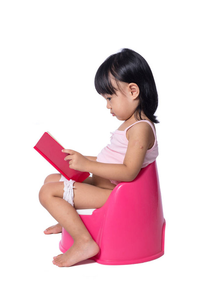 Asian chinese little girl sitting on chamberpot with book  - Фото, зображення