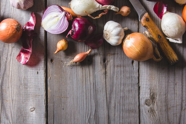 Several kinds of different onion bulbs lying on an old wooden table. - Photo, Image