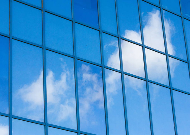 Texture, pattern, background. Reflection in building windows. Blue windows, clouds reflected in the windows - Photo, image