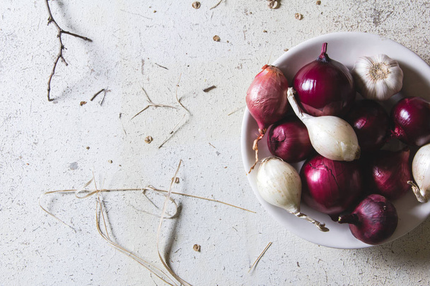 Red and white onion bulbs in the plate on old wooden painted table - Fotó, kép