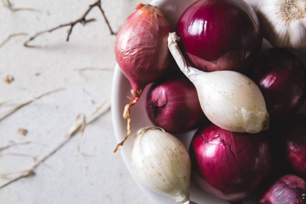 Red and white onion bulbs in the plate on old wooden painted table - Photo, image
