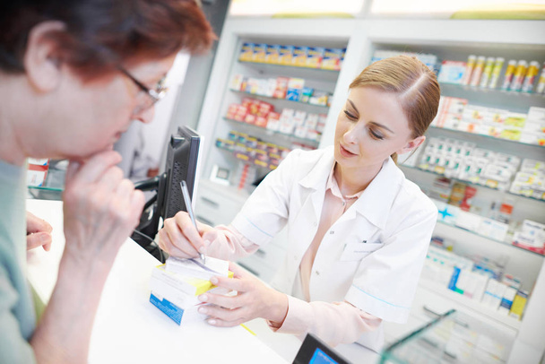Young pharmacist helping elderly customer - Photo, Image