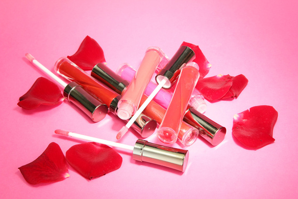 beautiful lip glosses with rose petals, on pink background - Photo, image