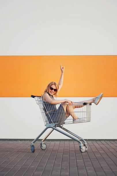 beautiful blonde girl sitting in shopping basket - Foto, Bild