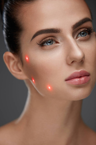 Primo piano di bella donna faccia con punti laser sulla pelle facciale
 - Foto, immagini