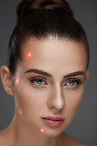 Close-up van de mooie vrouw gezicht met Laser punten op de huid van het gelaat - Foto, afbeelding