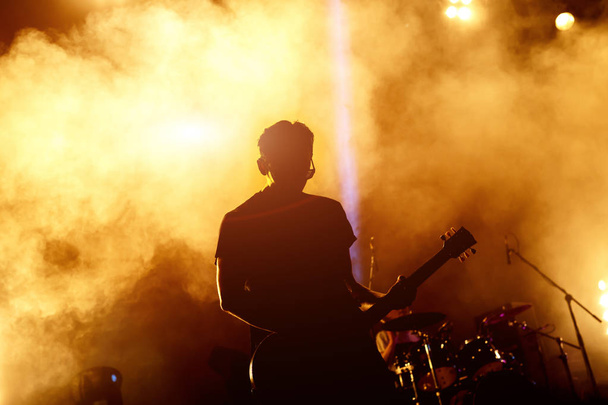 silueta de jugador de la guitarra en acción en el escenario - Foto, Imagen