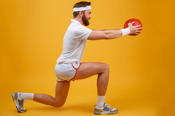 Concentrated young sportsman make sport exercises holding ball. - Foto, Bild