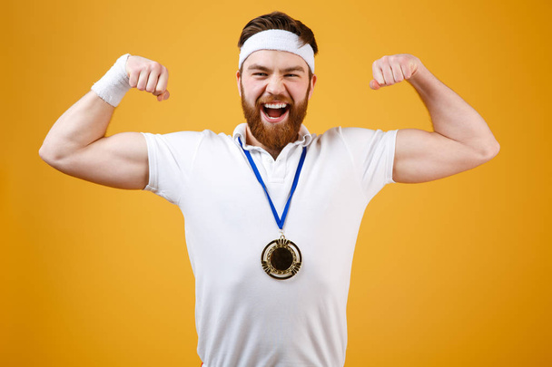 Emotional young sportsman with medal showing his biceps - Photo, Image