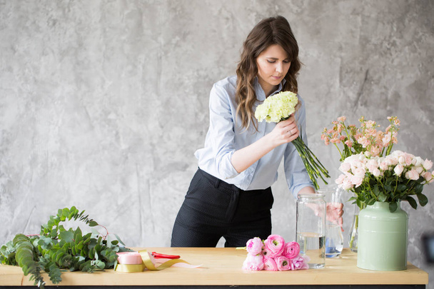 Florist at work: pretty young woman making fashion modern bouquet of different flowers - Fotoğraf, Görsel