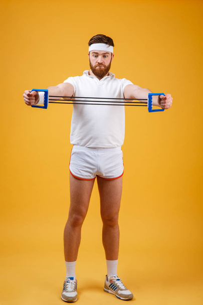 Young athletic man exercising with chest expander or resistance band - Fotoğraf, Görsel