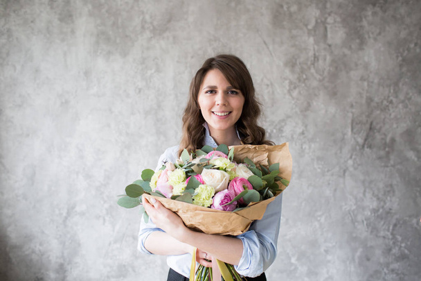 Bloemist op het werk: mooie jonge vrouw mode modern boeket van verschillende bloemen maken - Foto, afbeelding