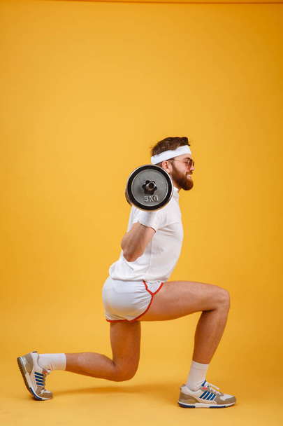 Side view of a retro fitness man doing squats with barbell - Foto, imagen
