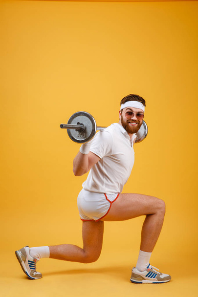 Side view of a retro fitness man doing squats with barbell - Zdjęcie, obraz