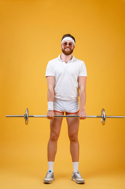 Cheerful young sportsman make sport exercises with barbell - Foto, imagen