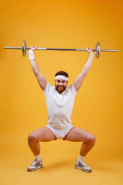 Full length of athletic man doing squatting exercises with barbell - Fotoğraf, Görsel