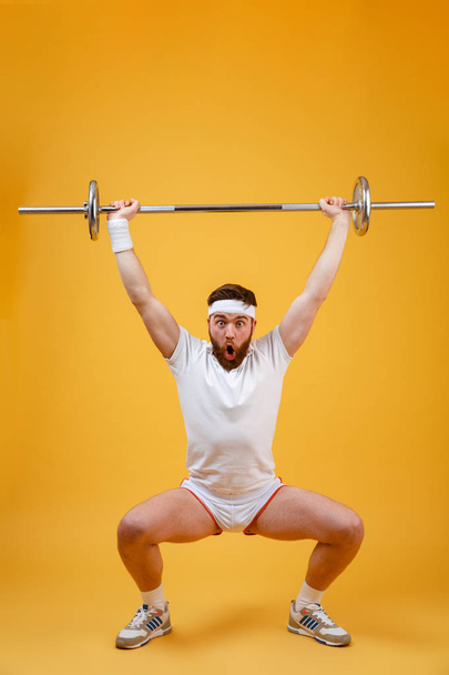 Full length portrait of a fitness man squatting with barbell - Foto, Imagem