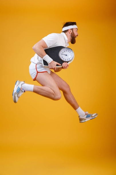 Screaming young sportsman jumping holding scales - Photo, Image