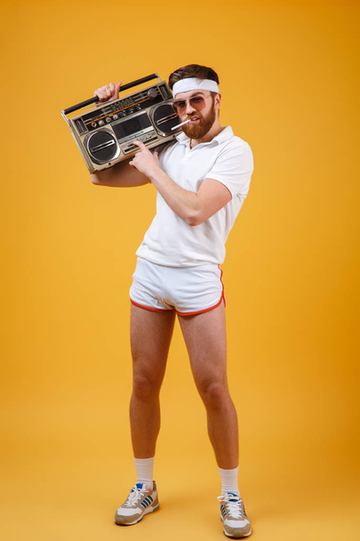 Serious young man wearing sunglasses holding tape recorder - Valokuva, kuva