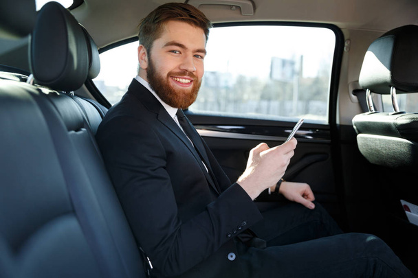 Side view of Smiling bearded business man in car - Zdjęcie, obraz