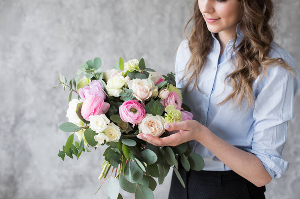 Florist at work: pretty young woman making fashion modern bouquet of different flowers - Fotó, kép