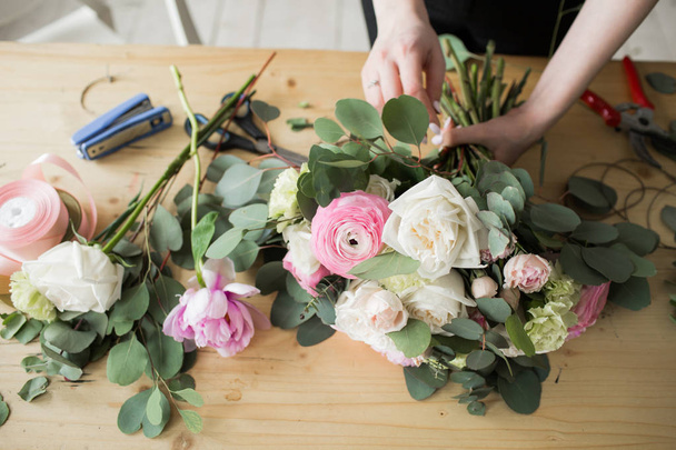 Floristin bei der Arbeit: Hübsche junge Frau macht Mode modernen Strauß aus verschiedenen Blumen - Foto, Bild