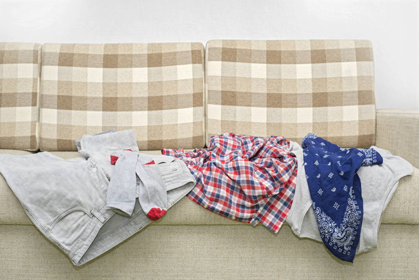 zerknitterte Kleidung auf Sofa liegend - Foto, Bild