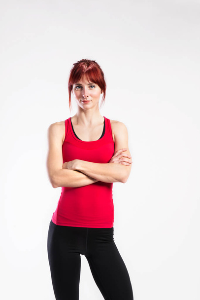 Attractive young fitness woman in red tank top. Studio shot. - Photo, image