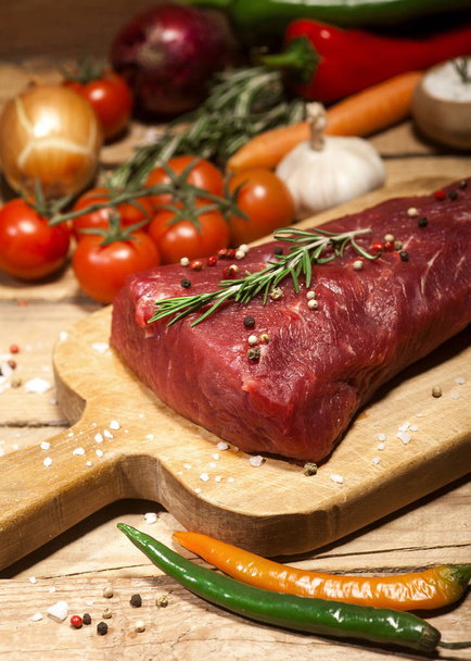 Raw beef steak on a cutting board with rosemary and spices. - Photo, Image
