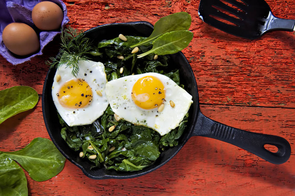 Eggs on spinach with pine nuts  - Photo, Image